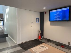 A bathroom door with a safety-orange cone on the floor nearby.
