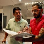 Carlos Ramírez and Edward Ossa stand and look at documents in a binder together.