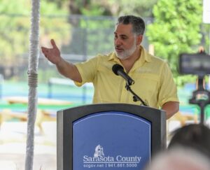 Joe Neunder gesticulating while speaking at a podium.