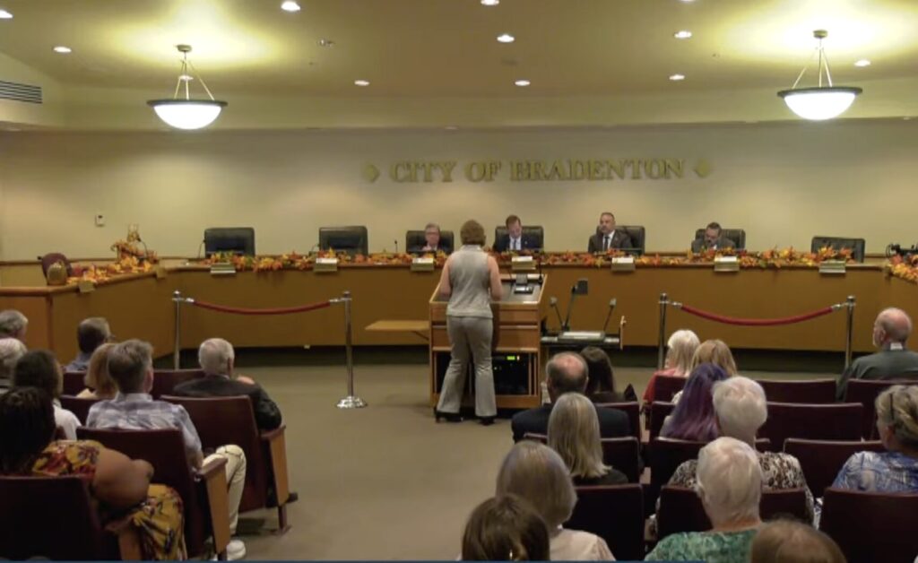 A person speaking at a podium at a meeting at Bradenton City Hall.