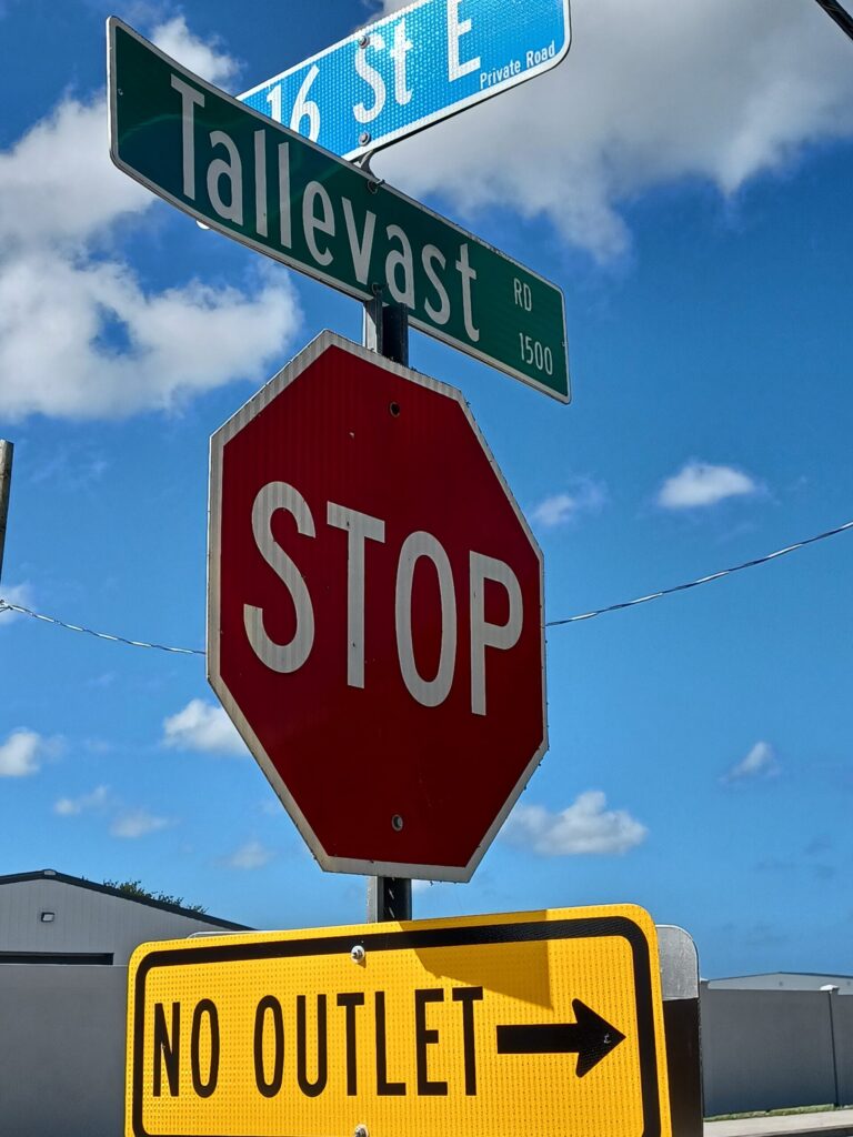 A stop sign with a street sign for Tallevast above and a no outlet sign below.