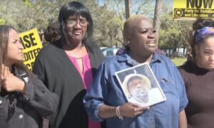 Tracey Washington holding a photo of Breonte Johnson-Davis while standing in a crowd with other demonstrators.