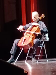 Anthony Cooke playing cello on stage.