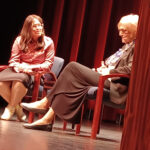 Sora Vigorito sitting with another person on stage.