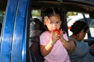 A child in a car eating an apple.