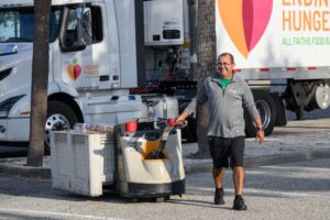 A deliveryperson pulling a crate of food for loading onto a truck.