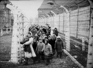 Black and white photo of a large crowd of children behind a barbed wire fence.