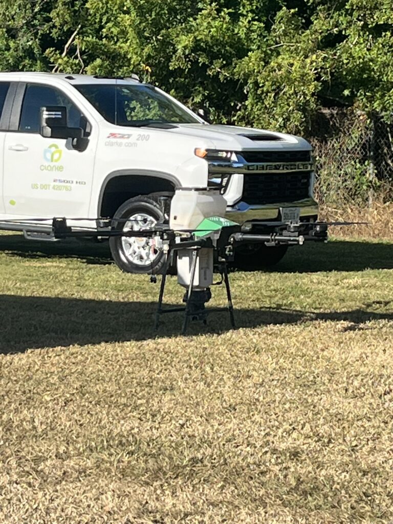 A drone on the ground near a truck with Clarke branding.