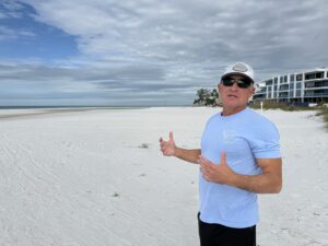 Michael Holderness standing on the beach and giving a double thumbs-up.