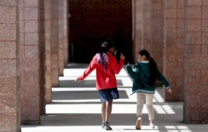 Two elementary school children walk down a hallway.