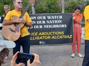 Demonstrators hold a banner that reads "Not on our watch; not in our nation; not to our neighbors" and "Stop ICE abductions; close Alligator Alcatraz".