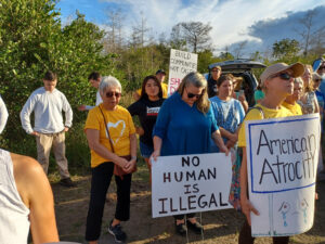 Demonstrators hold signs including "No human is illegal" and "American Atrocity".