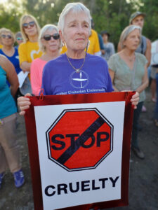 A demonstrator holds a sign that reads "Stop cruelty".