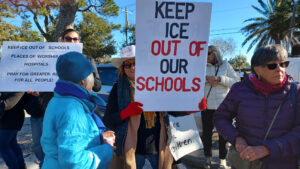 Demonstrators holding anti-ICE signs including "Keep ICE out of our schools".