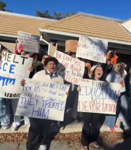 Protesters holding anti-ICE signs including "Fund education not deportation", "ICE doesn't make us feel safer", and "Jesus did not die so that we could treat others how they treated him".