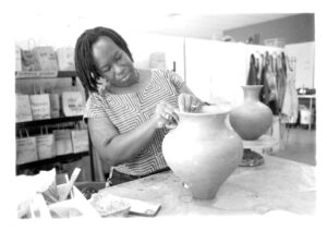 Osa Atoe sculpting a clay vase.