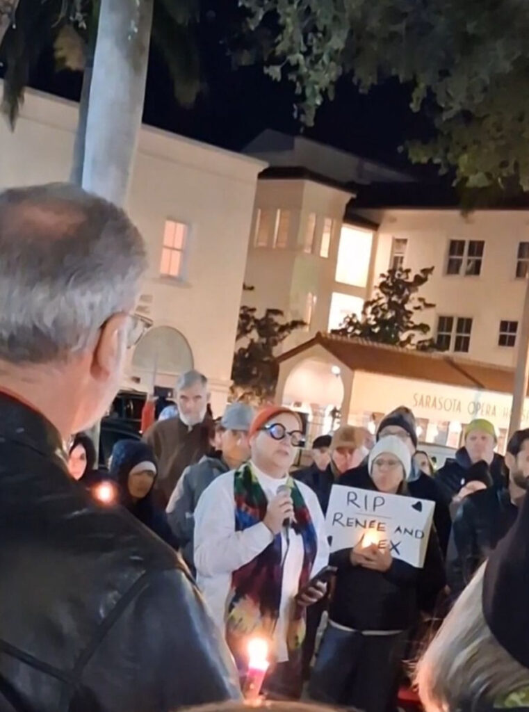 A crowd gathered in downtown Sarasota for a candlelit vigil. One demonstrator holds a sign that reads "RIP Renee and Alex".