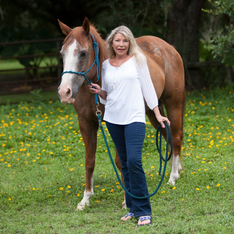 Carol Ann Felts smiling while walking alongside a horse.