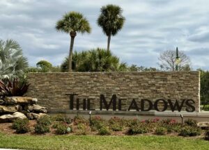 A sign at the entrance to a community that reads "The Meadows".
