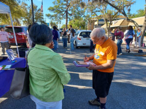 Someone signs a petition near a crowd of demonstrators assembled outside the Sarasota County School District's central office.
