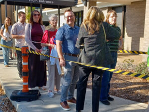 A line of people fenced in by hazard tape stands outside the Sarasota County School District's central office.