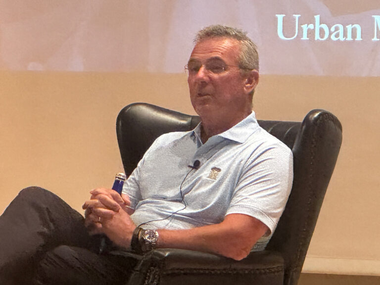 Urban Meyer reclining in a chair on stage.