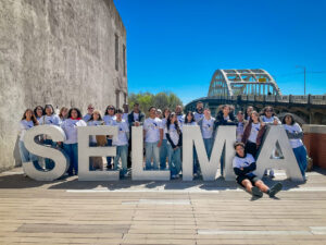 Students pose for a photo around big block letters that read "Selma".