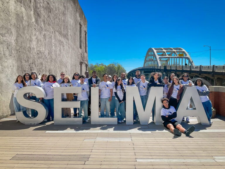 Students pose for a photo around big block letters that read "Selma".