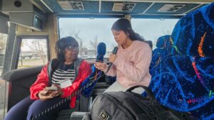 A student speaks with Dr. Martha Bouyer on a bus.