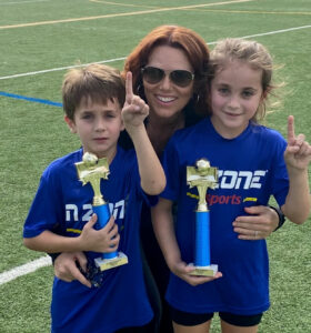 Teresa DeWitt and her two children, both of whom hold soccer trophies.