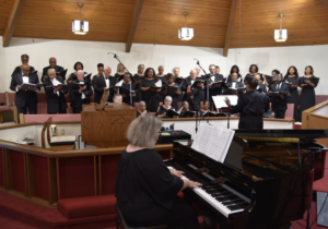 Members of the Gulf Coast Community Choir singing while a pianist plays.