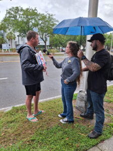 Kaitlin Bennett holds up a microphone to a demonstrator blowing a whistle.