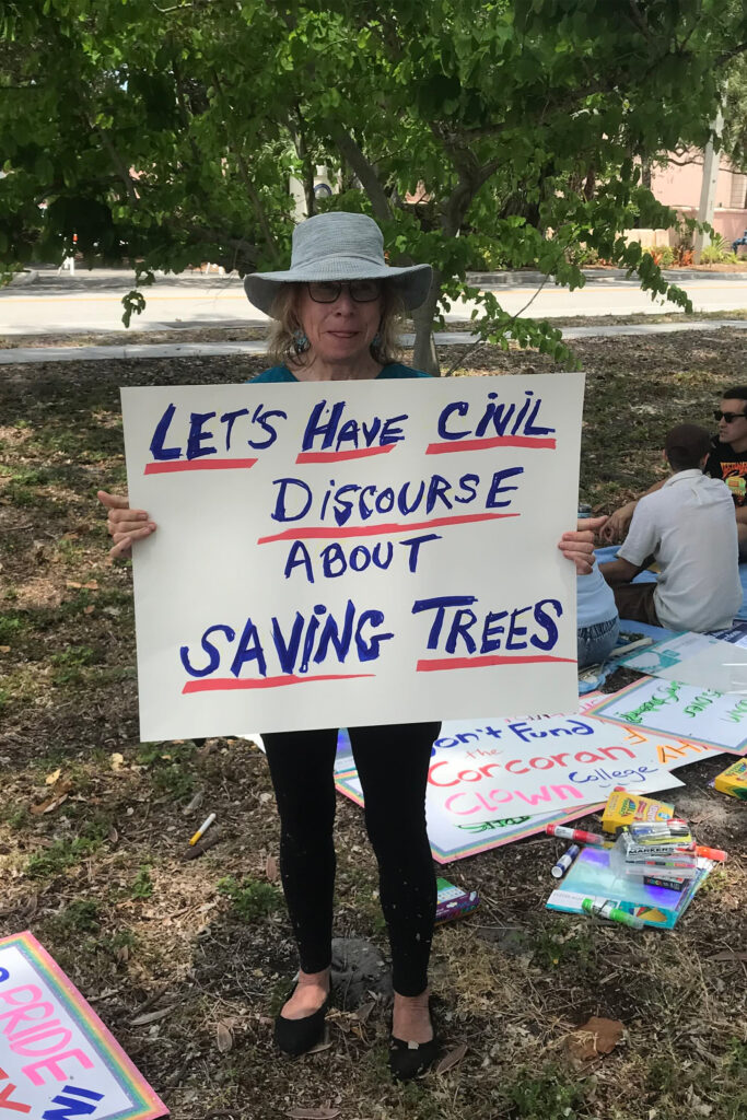 A demonstrator holds up a sign that reads, "Let's have civil discourse about saving trees".