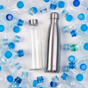 A glass water bottle and a metal water bottle surrounded by empty plastic water bottles.