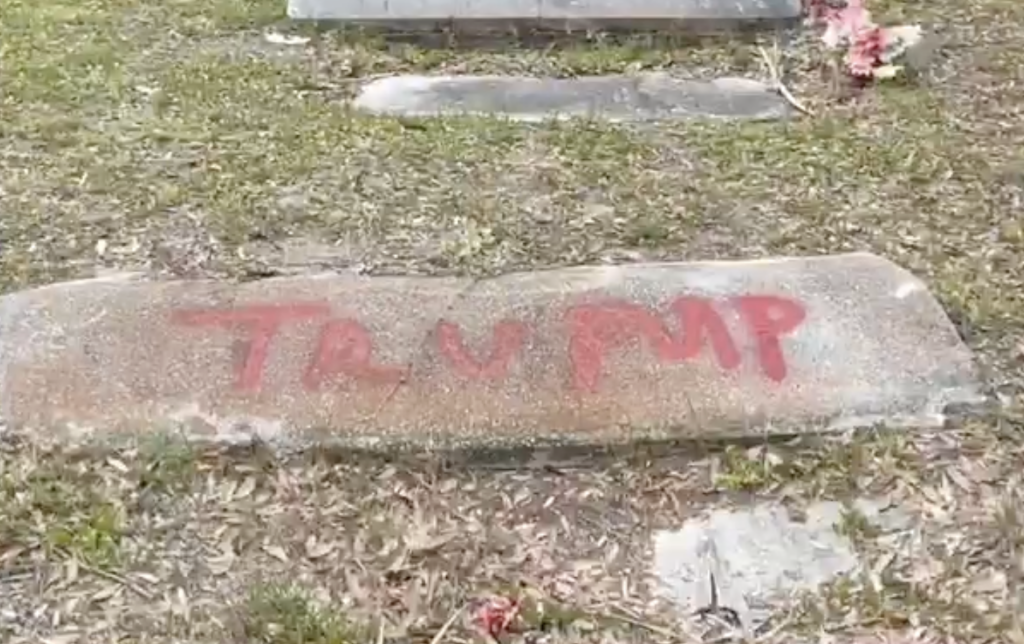 Spray-painted letters that read "Trump" on a neglected headstone.
