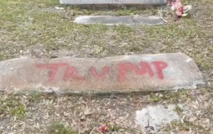 Spray-painted letters that read "Trump" on a neglected headstone.
