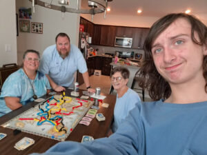 Allen Spence and three family members around a dining table playing a board game.