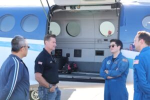 Stewube standing near to a plane next to people in NOAA uniforms.