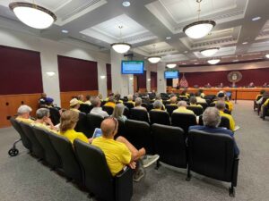 A packed crowd composed mostly of people wearing yellow shirts at a Sarasota County Commission meeting.