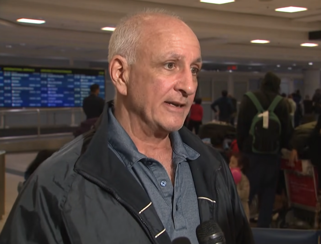 Douglas Dixon being interviewed in an airport.