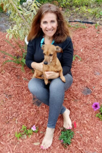 Julie London holding a dog in her lap and smiling.