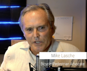 Mike Lasche speaking. A lower third labels him "Mike Lasche: Bicycle/Pedestrian Advocate".