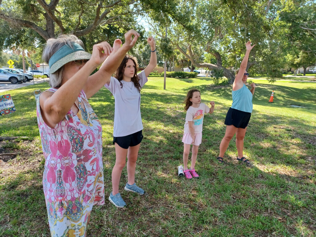 Four people stand outside and stretch.
