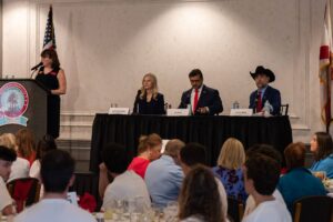 Sydney Gruters, Ed Pope and Eddie Speir seated at a table together on stage.