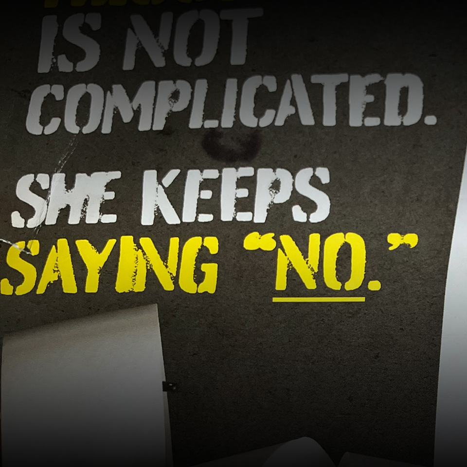 Close-up of text on a flyer that reads "She keeps saying 'no.'".