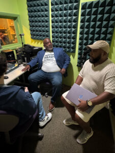 Jackson Rothman and Ed James III interviewing Desmond Meade in a sound studio.