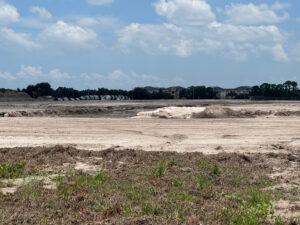 A field of dirt with pipes visible in the distance.