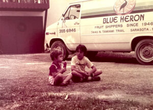 Faded photo of Kelly Kirschner as a child sitting with other child near a Blue Heron van.