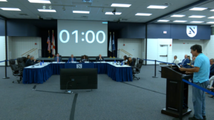 Rodrigo Diaz addresses the Board of Trustees. A one-minute timer is on the projector.