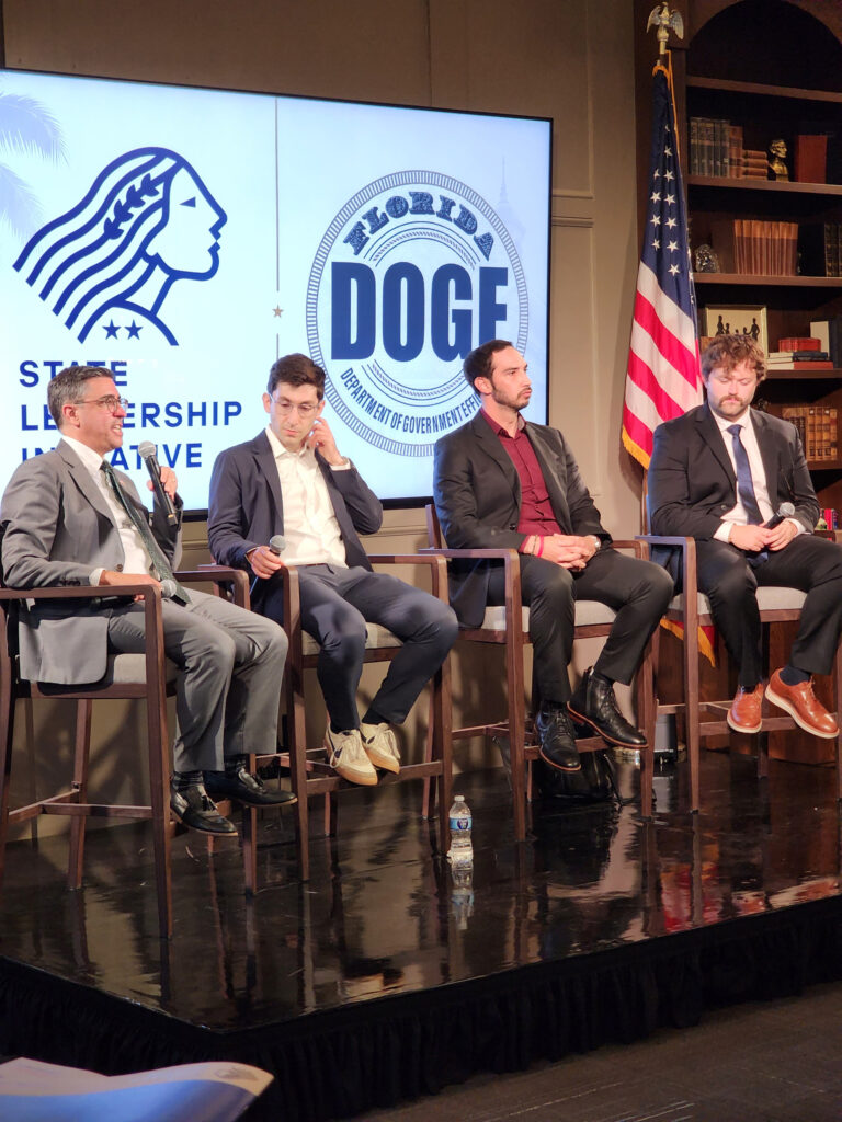 Eric Soskin and three other speakers on stage at a Florida DOGE event hosted by the State Leadership Initiative.